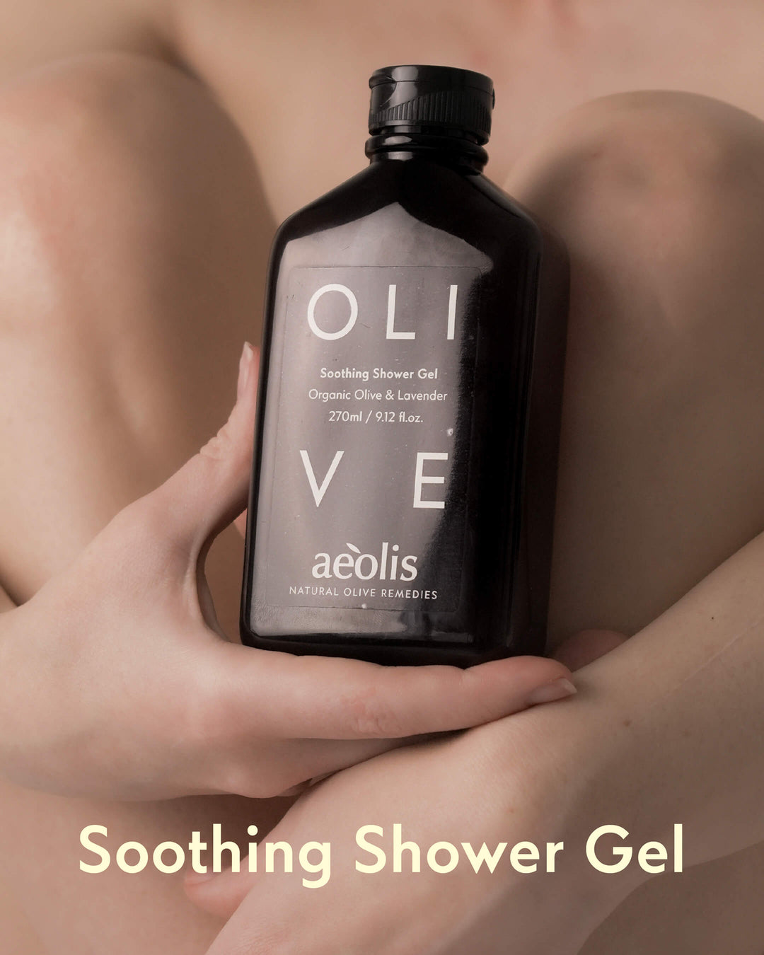 Hand holding a bottle of Aeolis olive Soothing Shower Gel against a blurred background