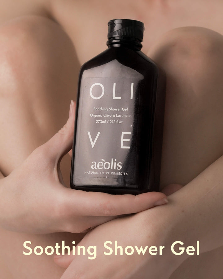 Hand holding a bottle of Aeolis olive Soothing Shower Gel against a blurred background