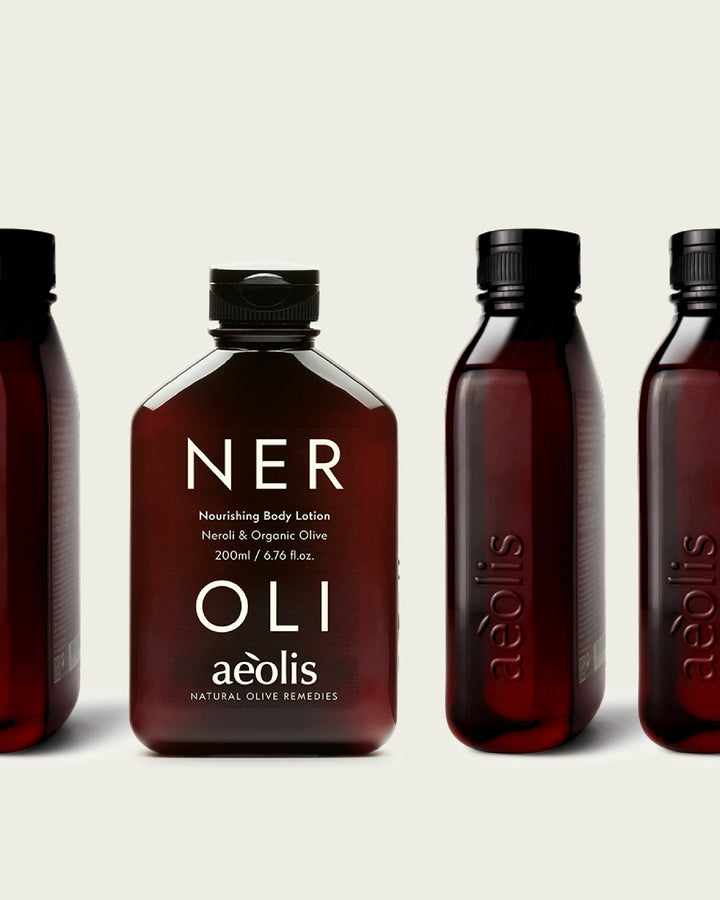 Four bottles of Aeolis Neroli Nourishing Body Lotion on a light beige background