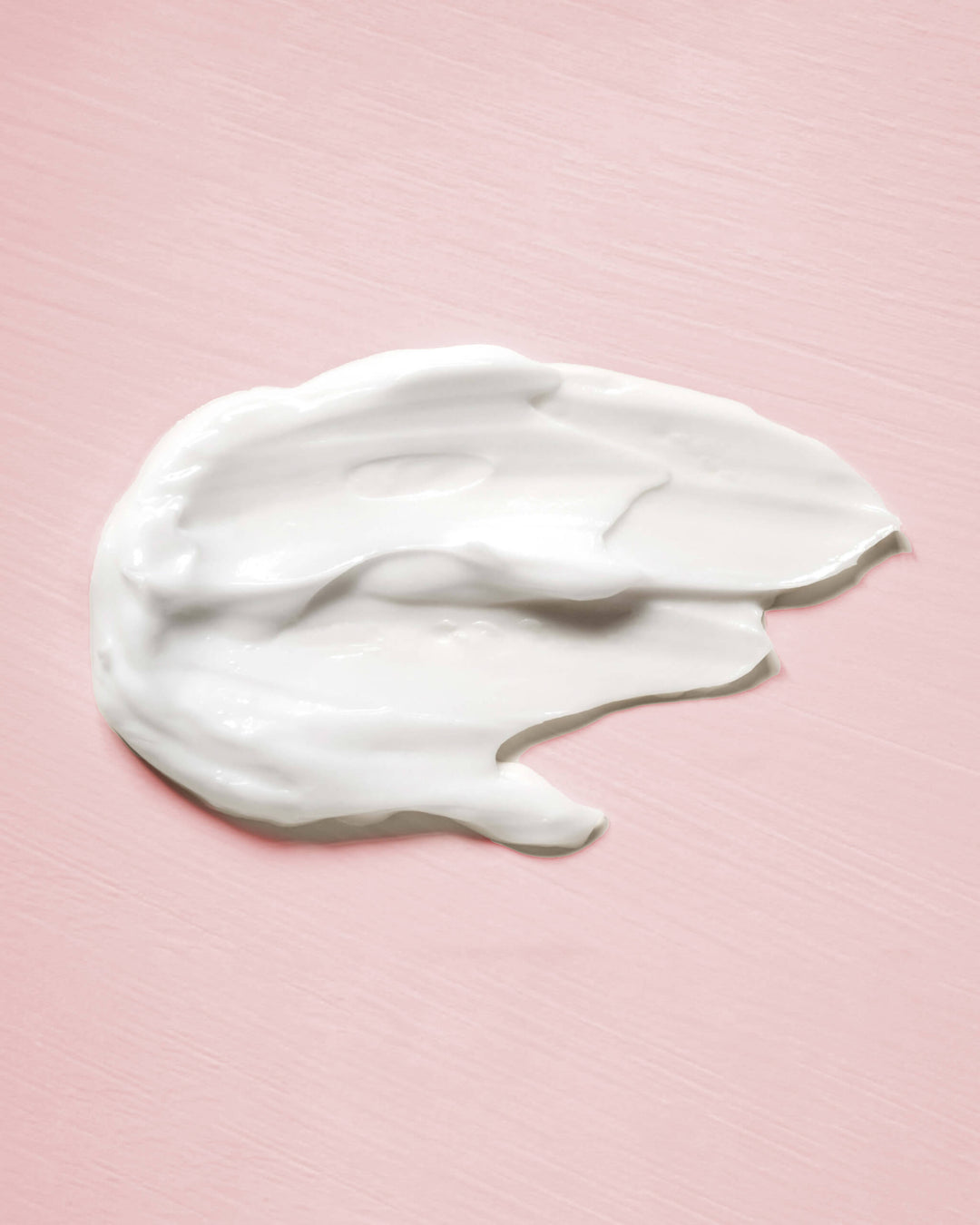 White cream smear on a pink background