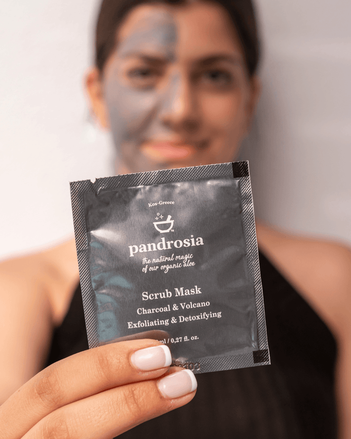 Person holding a pandrossia scrub mask packet with a blurred background