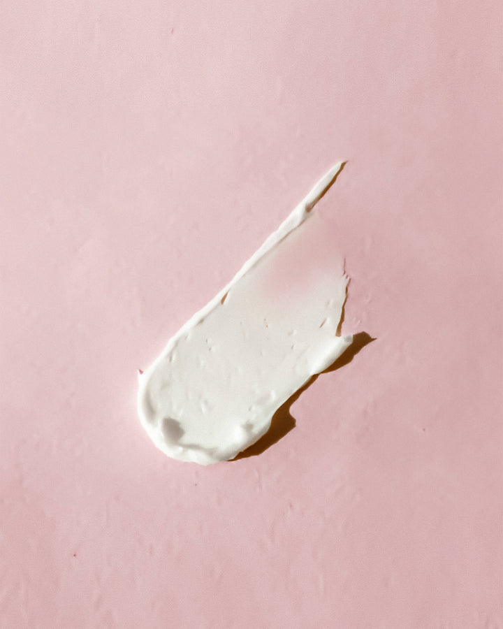 White cream smear on a pink background