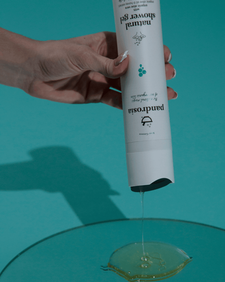 Hand holding a Pantosia shower gel bottle with a blue background